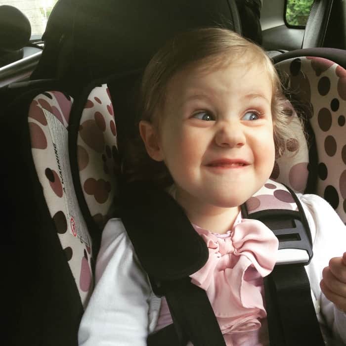 toddler pulling funny face in carseat