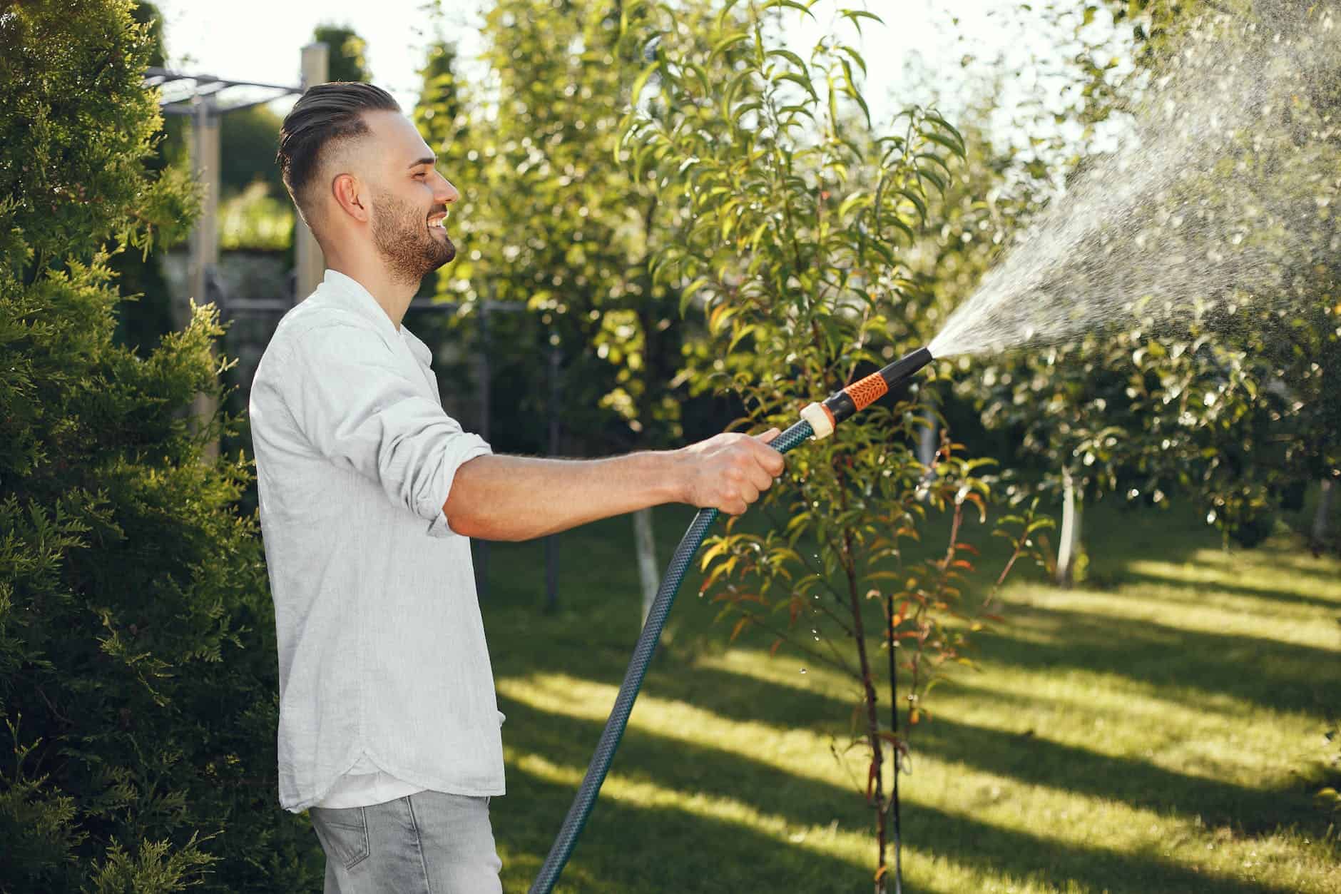 man in white long sleeve shirt watering plants