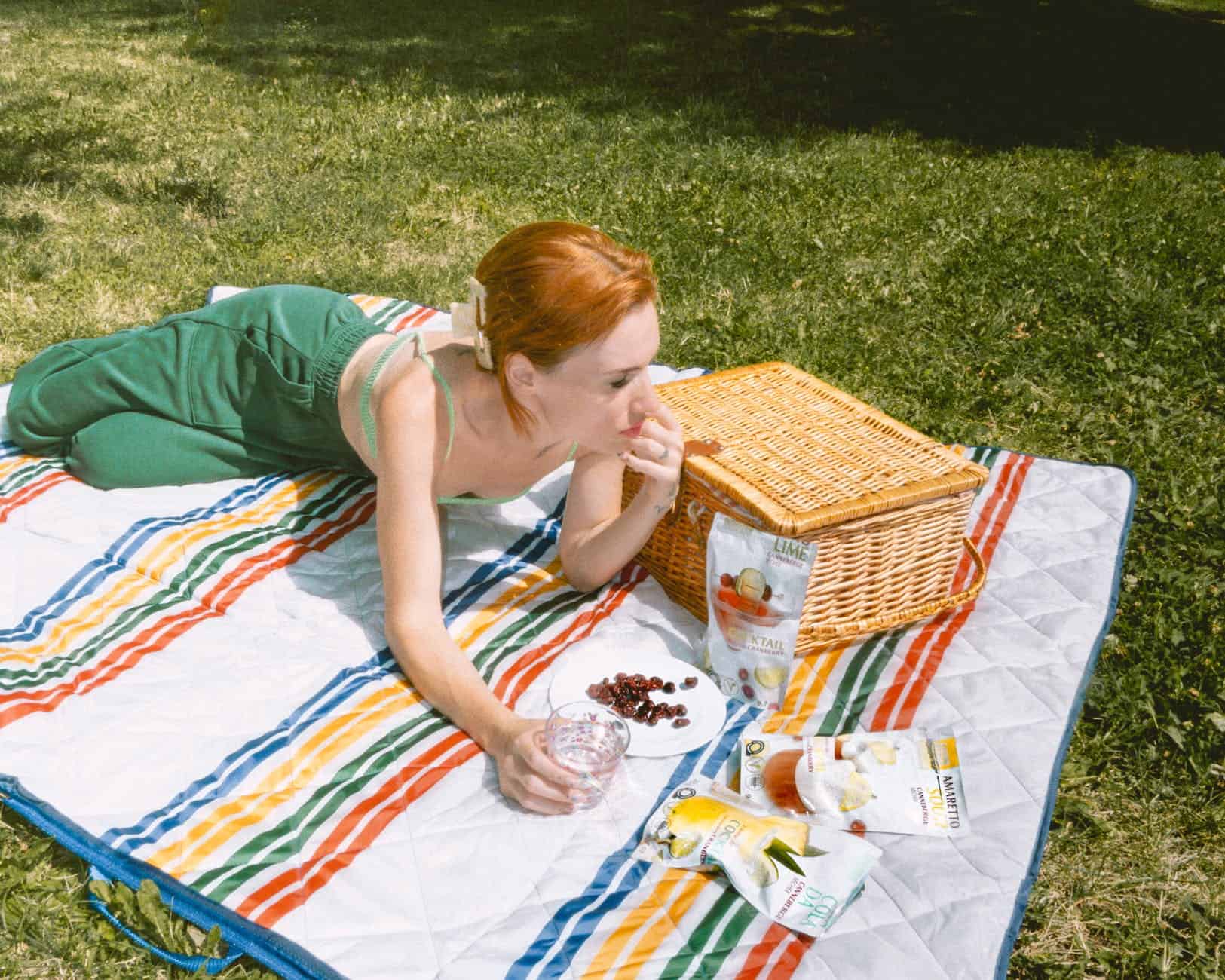 woman in green clothes lying down on picnic blanket