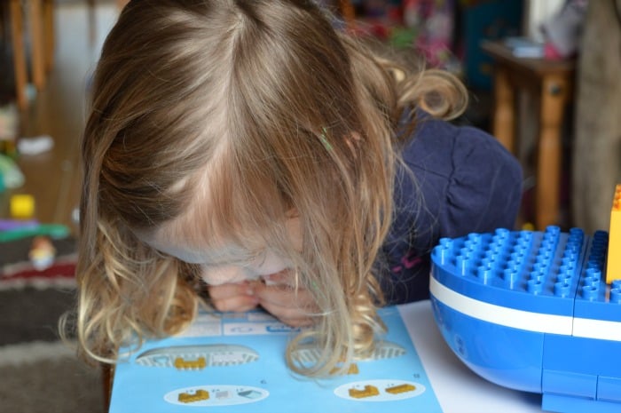 girl reading instructions to make toy boat