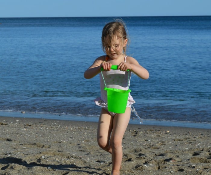 child playing with bucket by the sea