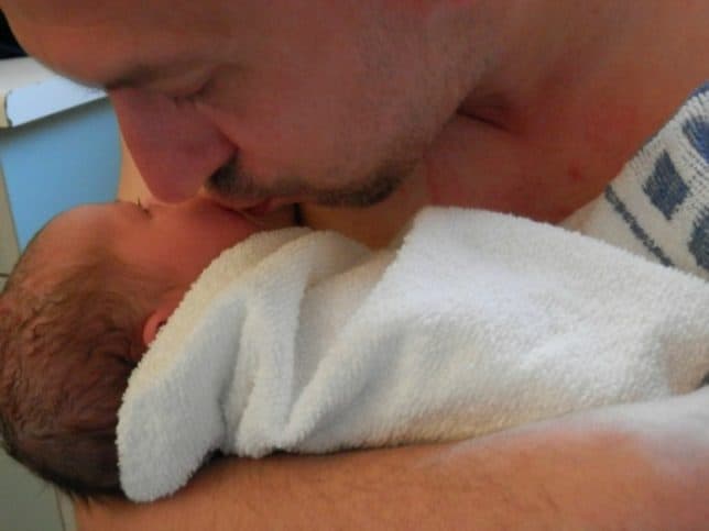 Dad kissing newborn baby on cheek 