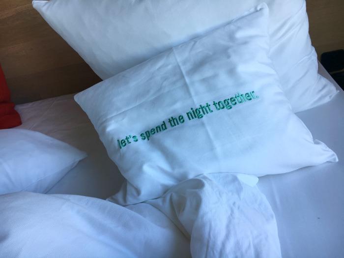 bikini hotel berlin bed with quote on pillow saying 'lets spend the night together'