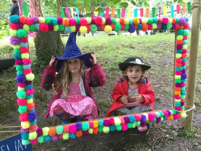 2 children in fancy dress posing for photo in decorated frame at Camp Bestival's Dingly Dell Wood 