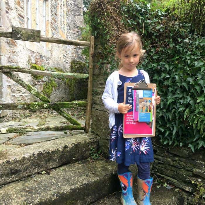 child by gate at Buckland Abbey Devon holding National Trust activity pack 