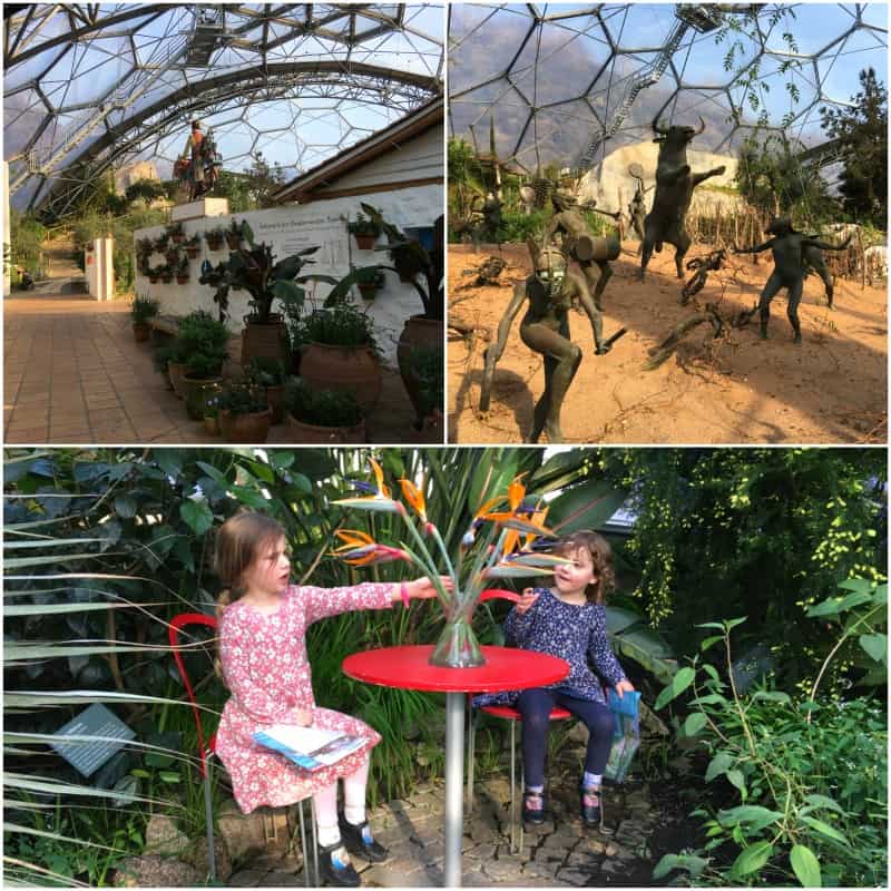 Inside the Mediterranean biome at Eden Project Cornwall with flowers, sculptures and two children sitting at a table with orange flowers surrounded by green plants