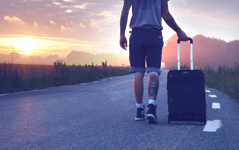 walking down road with suitcase