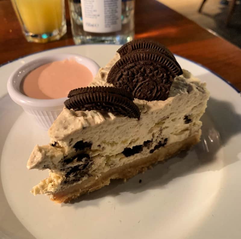 Oreo and White Chocolate Fudge Pie on white plate served with strawberry sauce