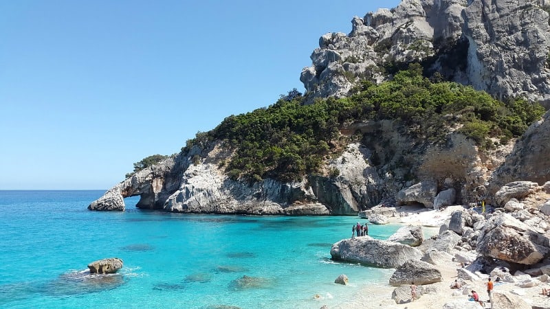beach and sea with people climbing on rocks cala goloritze sardina