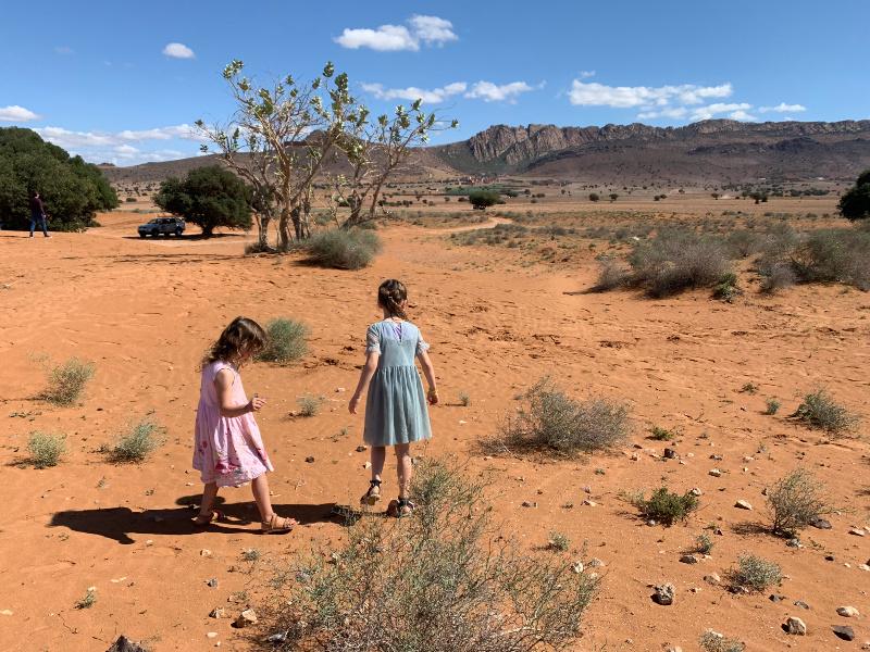 two children playing in the dessert with atlas mountains in distance