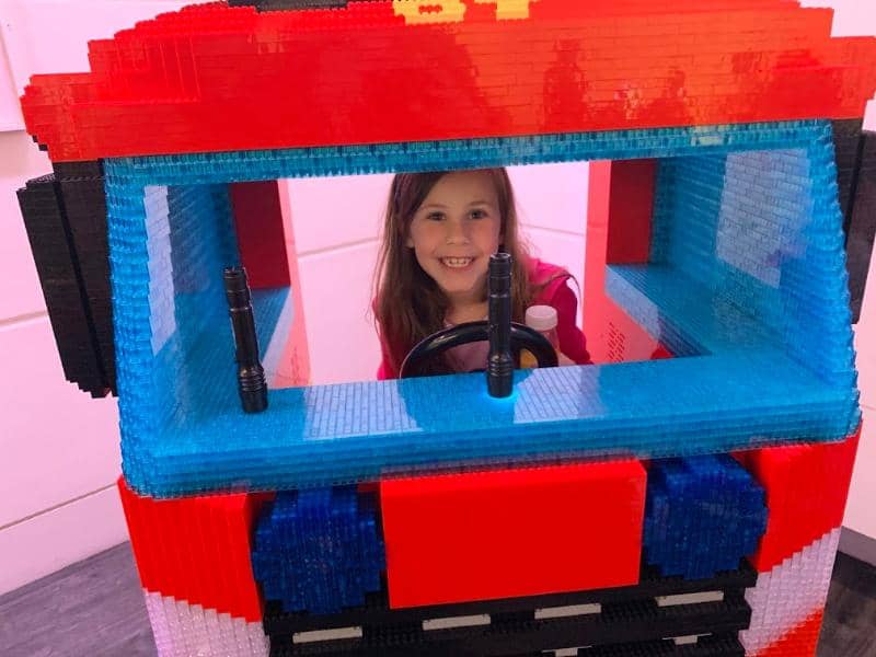 child in large lego fire truck model.