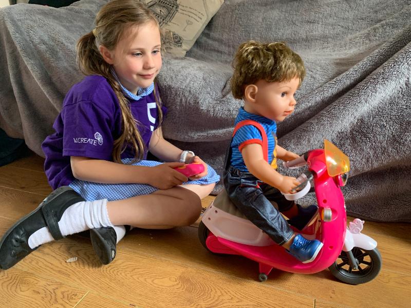 child playing with baby born remote control scooter