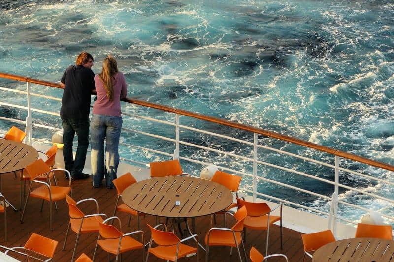 couple watching sea from deck of cruise ship