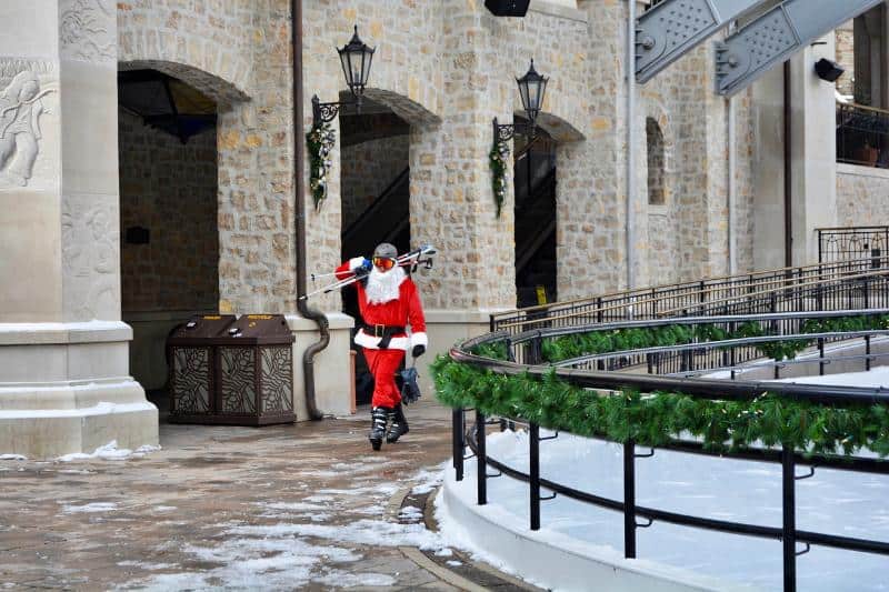 man dressed as santa claus carrying skis at resort (1)