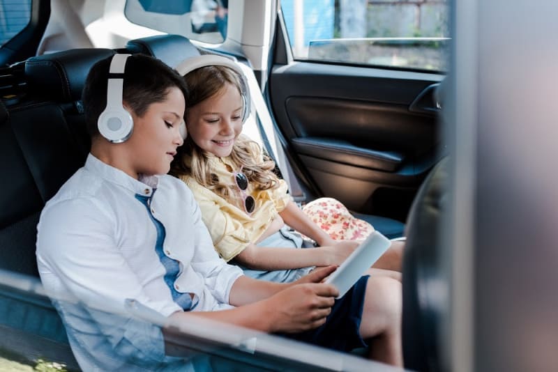 children wearing headphones in car