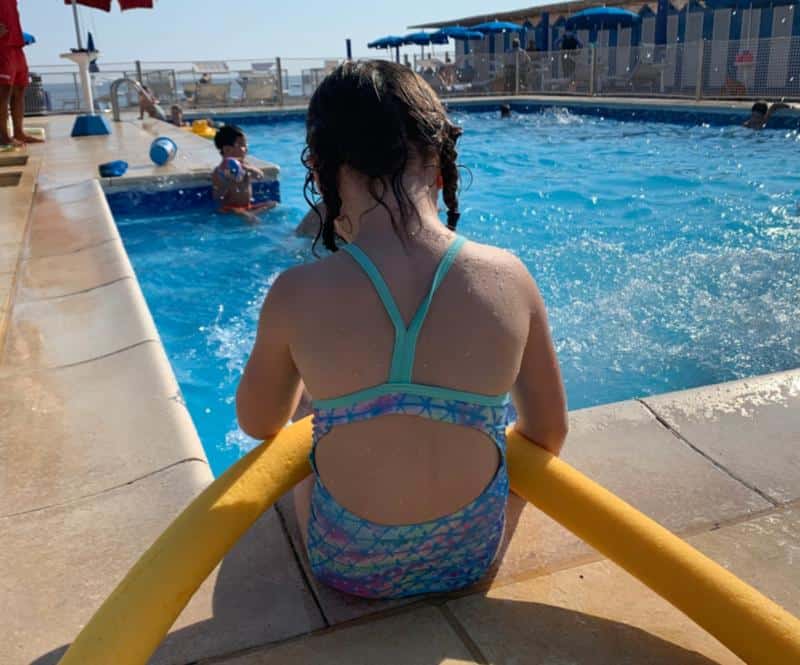 girl sitting on edge of swimming pool