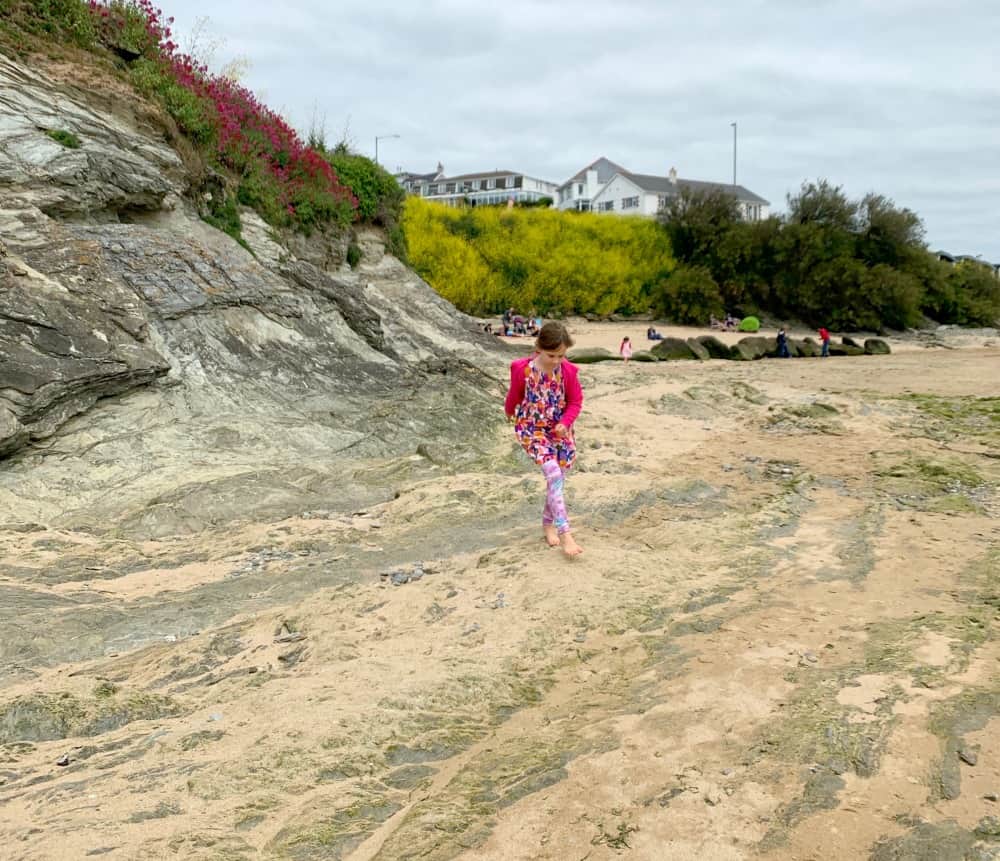 child exploring porth beach in cornwall