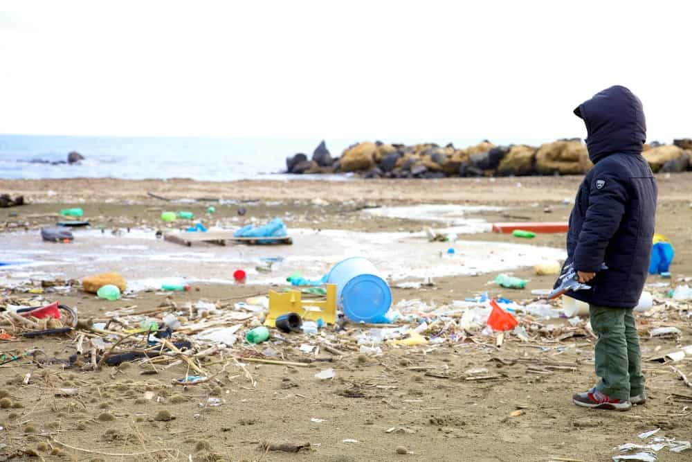 child looking at plastic pollution on beach