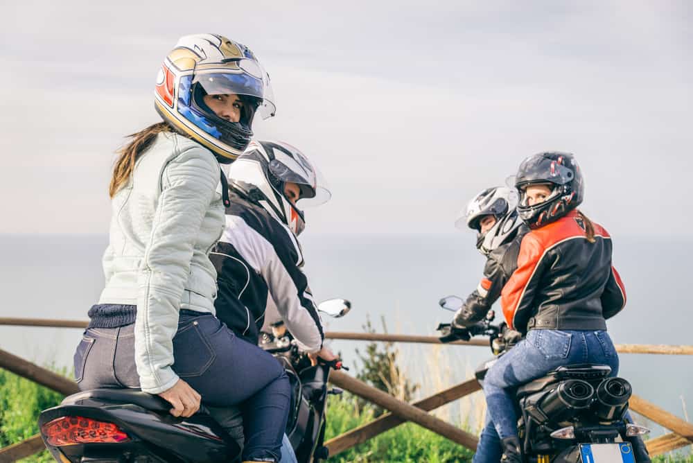 Two motorbikes driving in the nature - Friends driving racing motorcycles with their girlfriends - Group of bikers stop in a panoramic view point and look at suggestive sunset