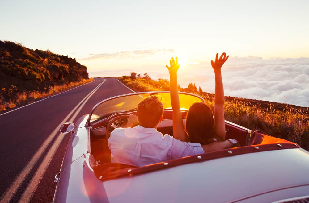 Driving into the Sunset. Romantic Young Couple Enjoying Sunset Drive in Classic Vintage Sports Car