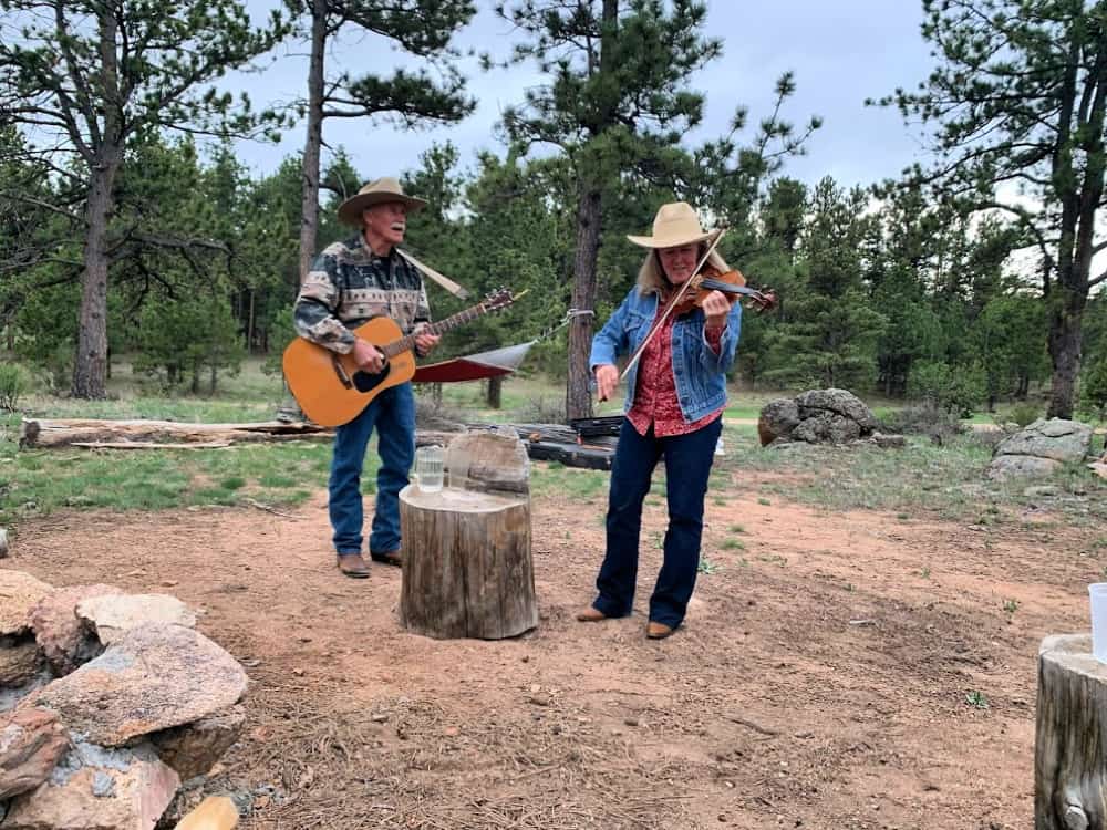 couple playing live music by campfire at dude ranch