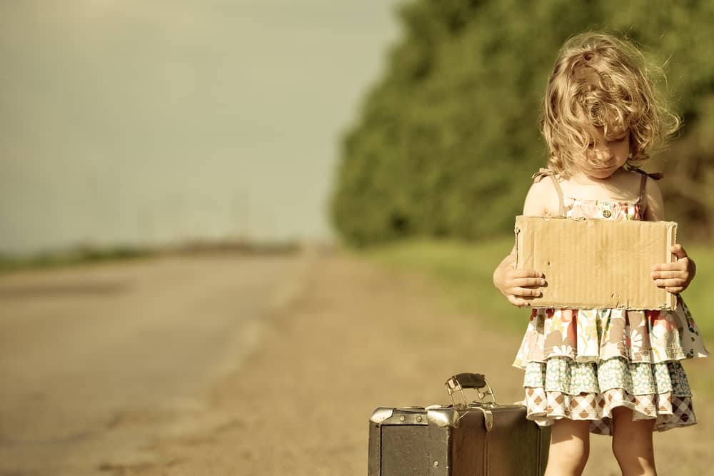 Lonely girl with suitcase standing about road and holding paper with copyspace in hands