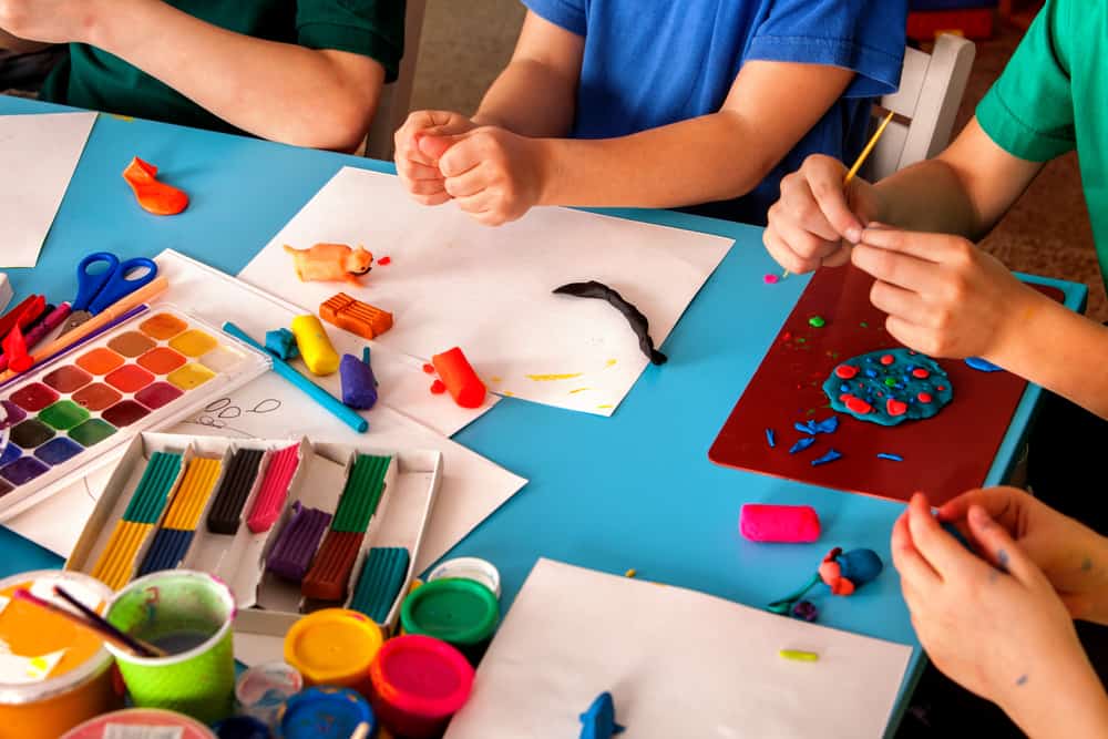 Plasticine modeling clay in children class. Teacher teaches kids together play dough and mold from plasticine in kindergarten or preschool. Development of fine motor skills of fingers.