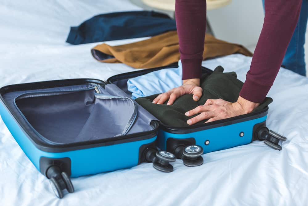 man packing carry on suitcase 