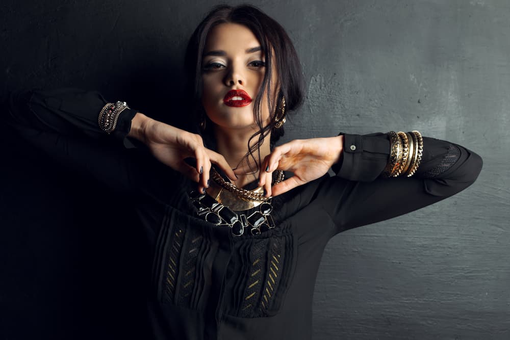 fashion studio portrait of gorgeous woman with dark hair and bright makeup with luxurious bijou, massive necklace and bracelets