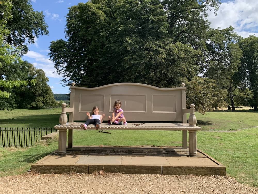 children sitting on oversized bench at belton house 