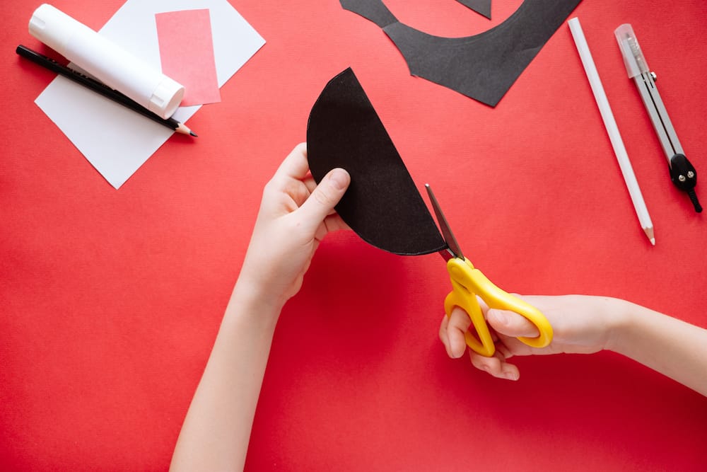 How to make bat out of paper at home. Hands making craft out of paper. Step by step photo instruction. Step 3. Cut the circles into two parts. Children DIY art project.