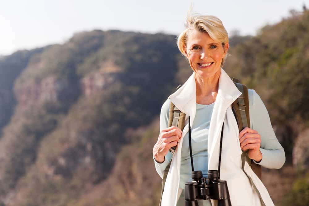 beautiful middle aged woman on top of the mountain with binoculars
