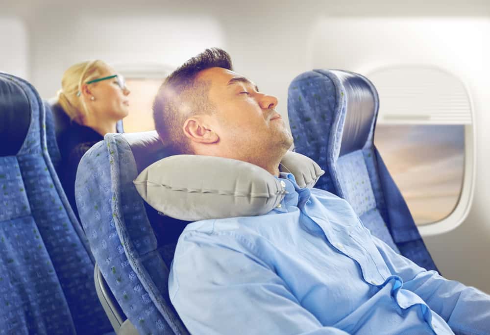 man using travel pillow on aeroplane 
