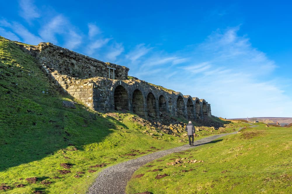 Old abandoned iron kilns at Rosedale in the North Yorkshire Moors, with a single man walking past on a path.