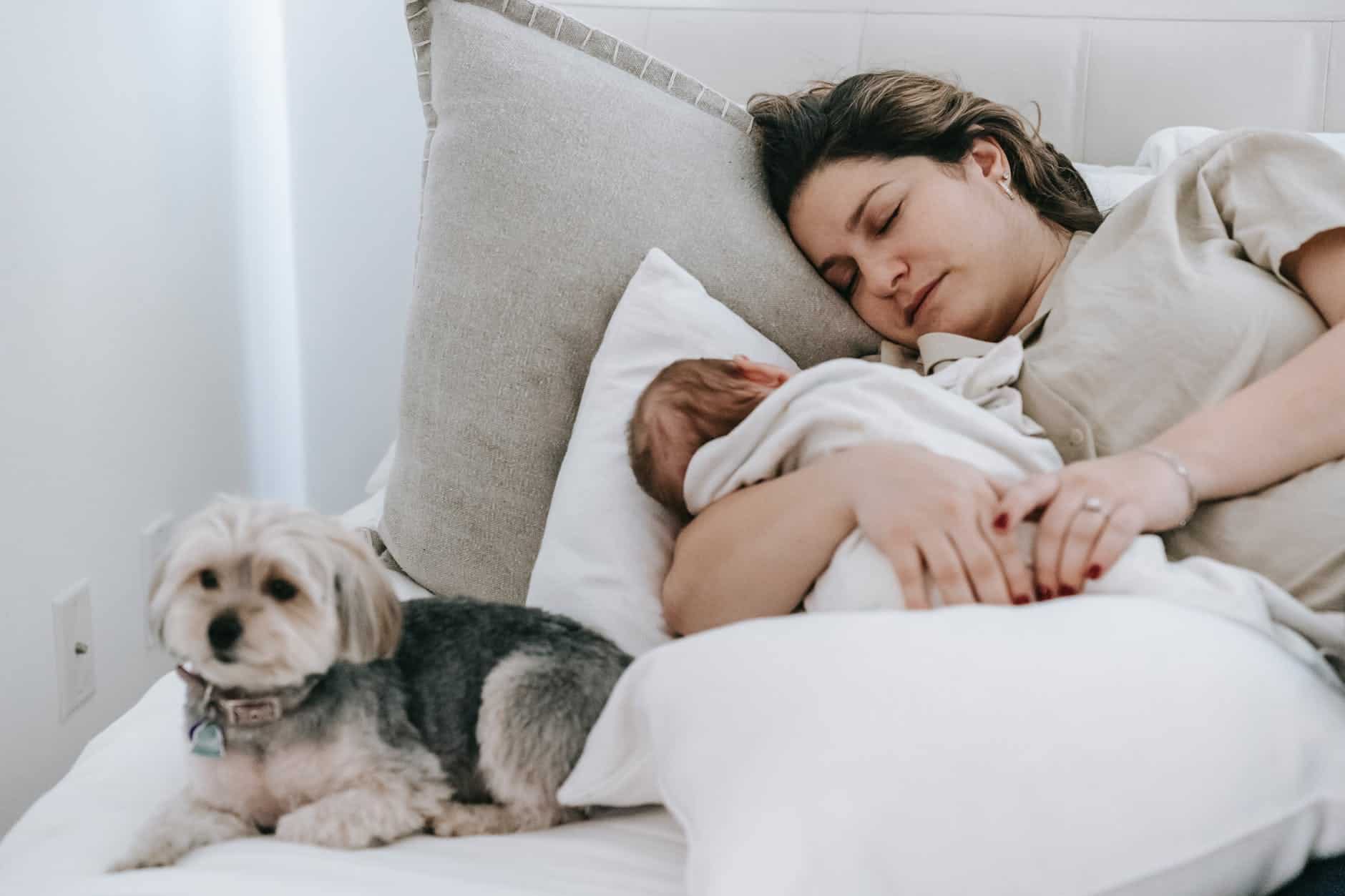mother with infant baby sleeping near dog