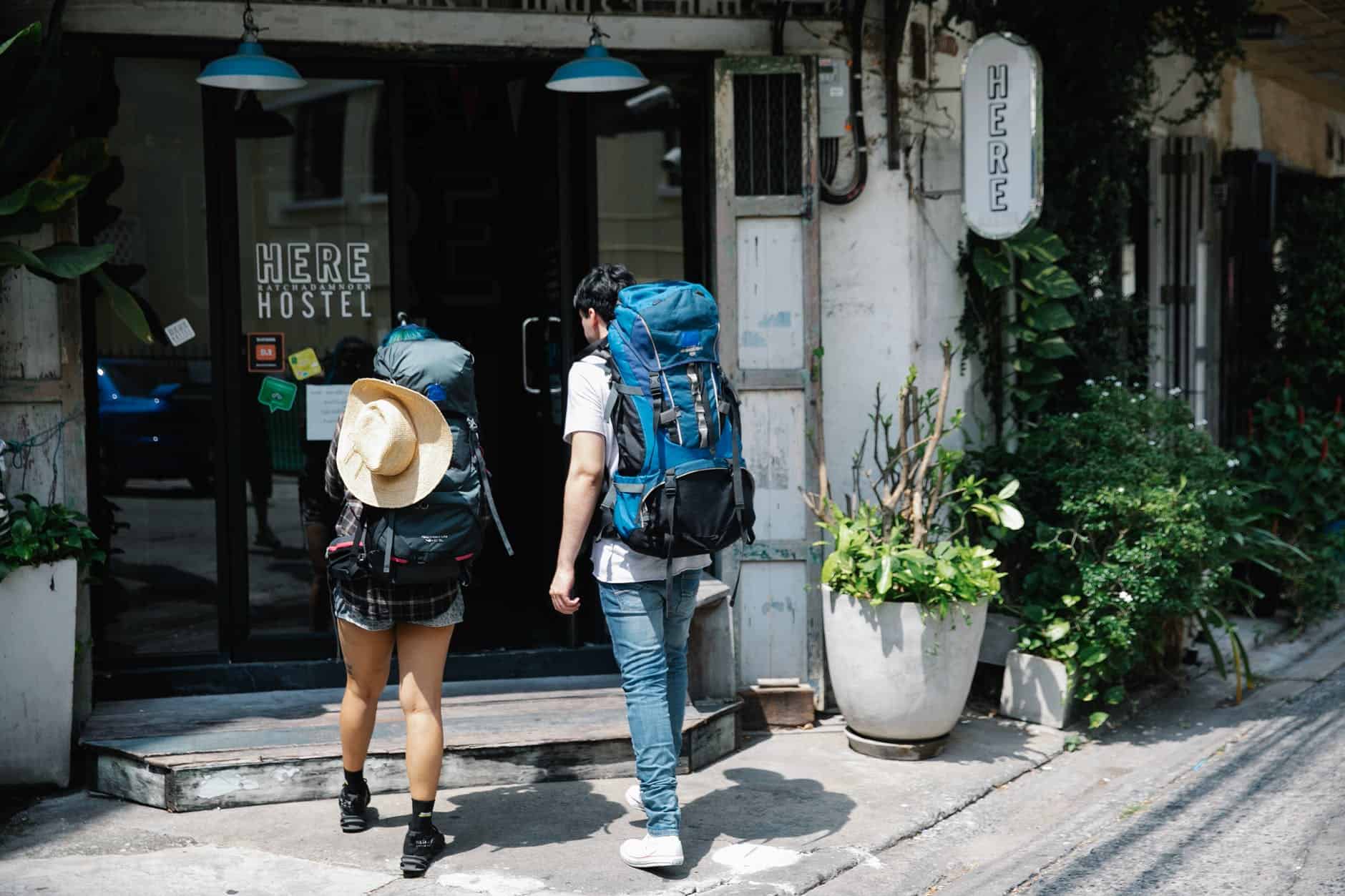 pexels-photo-7968283 unrecognizable couple of travellers with backpacks entering hotel