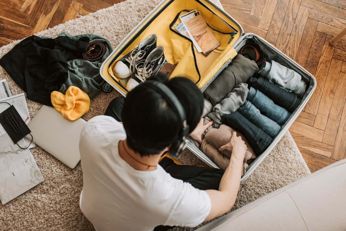 pexels-photo-7365337 a man listening on his headphones while packing his clothes