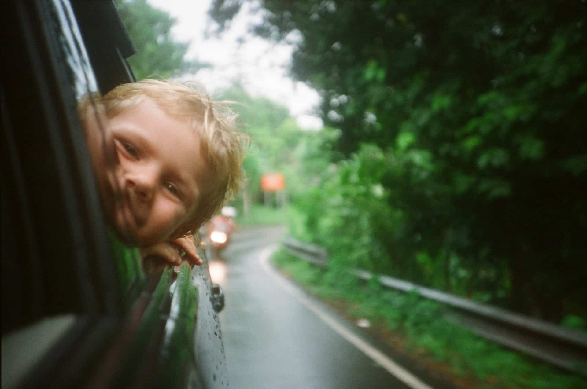 child poking head out of car window