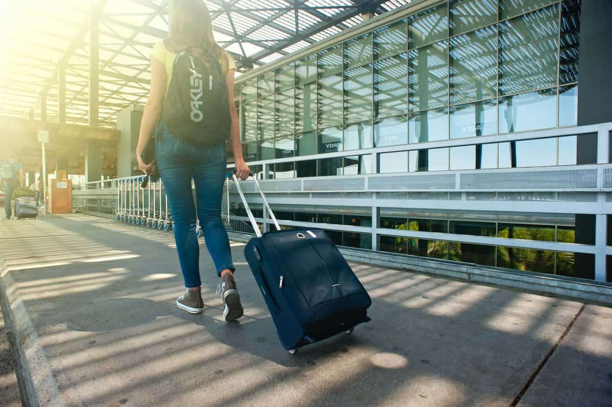 pexels-photo-1008155 woman walking on pathway while strolling luggage