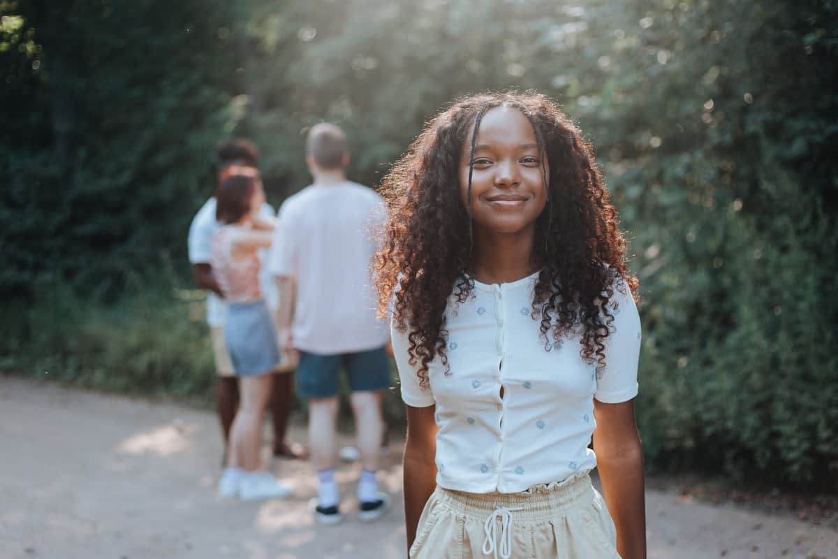 teenage girl smiling at camera with group of girls and boys in background