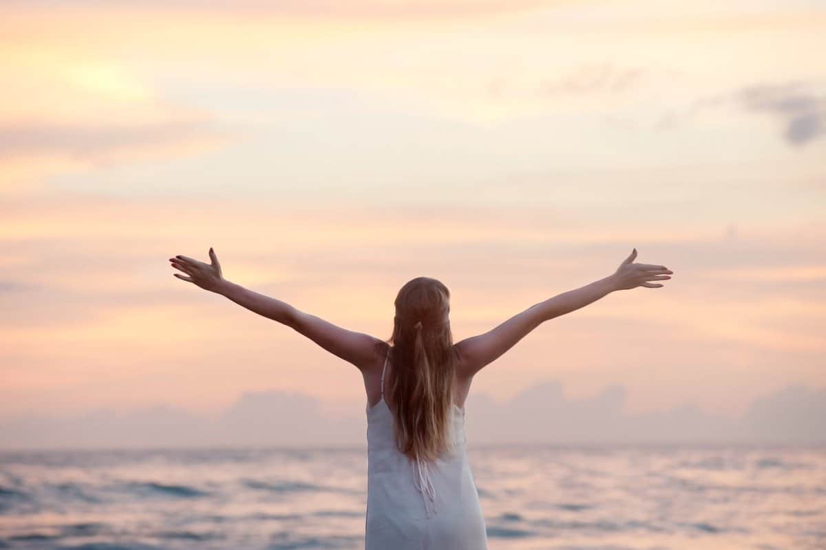 pexels-photo-320007 rear view of woman with arms raised at beach during sunset
