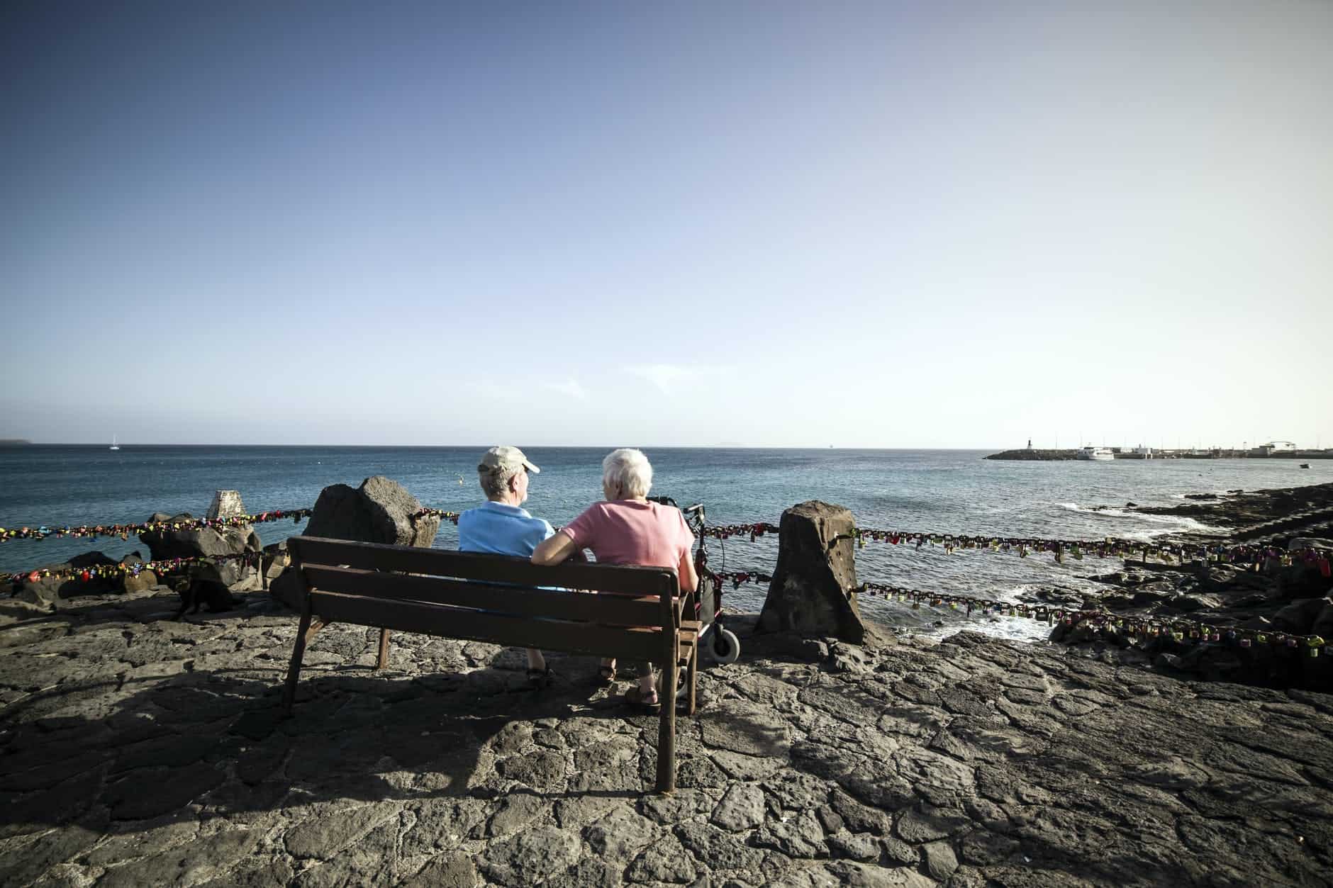 mature couple resting on bench in scenic seafront