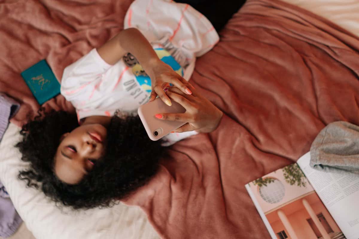 pexels-photo-6593793 young girl lying on bed holding a cellphone