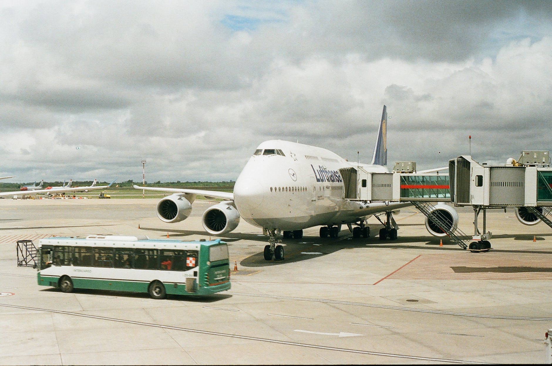 plane on airport with telescopic corridor attached and bus driving in front of it