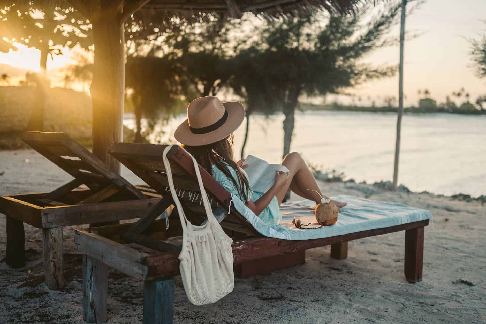 a woman lying on a sun lounger while reading a book