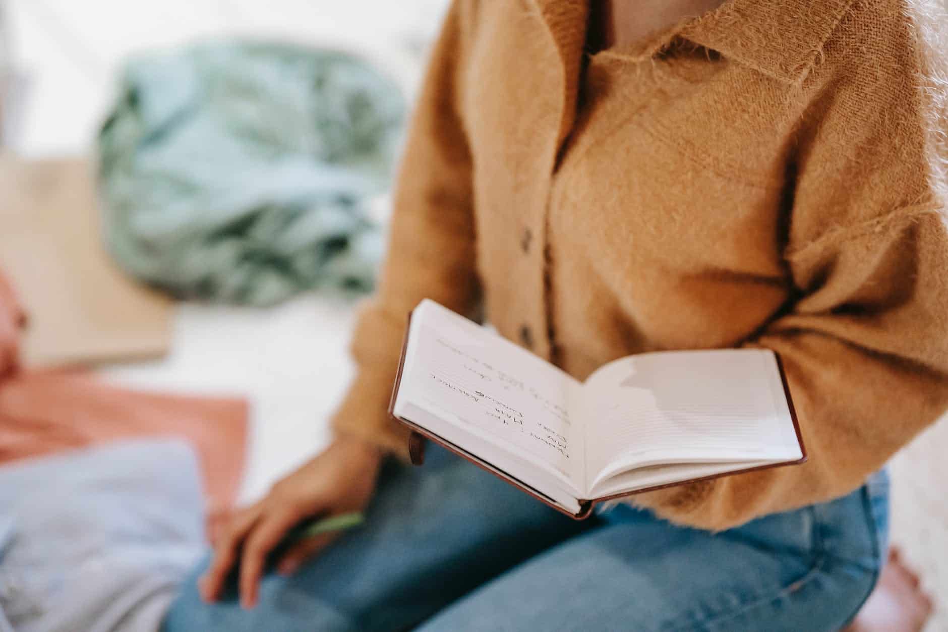 crop unrecognizable woman reading notes in diary