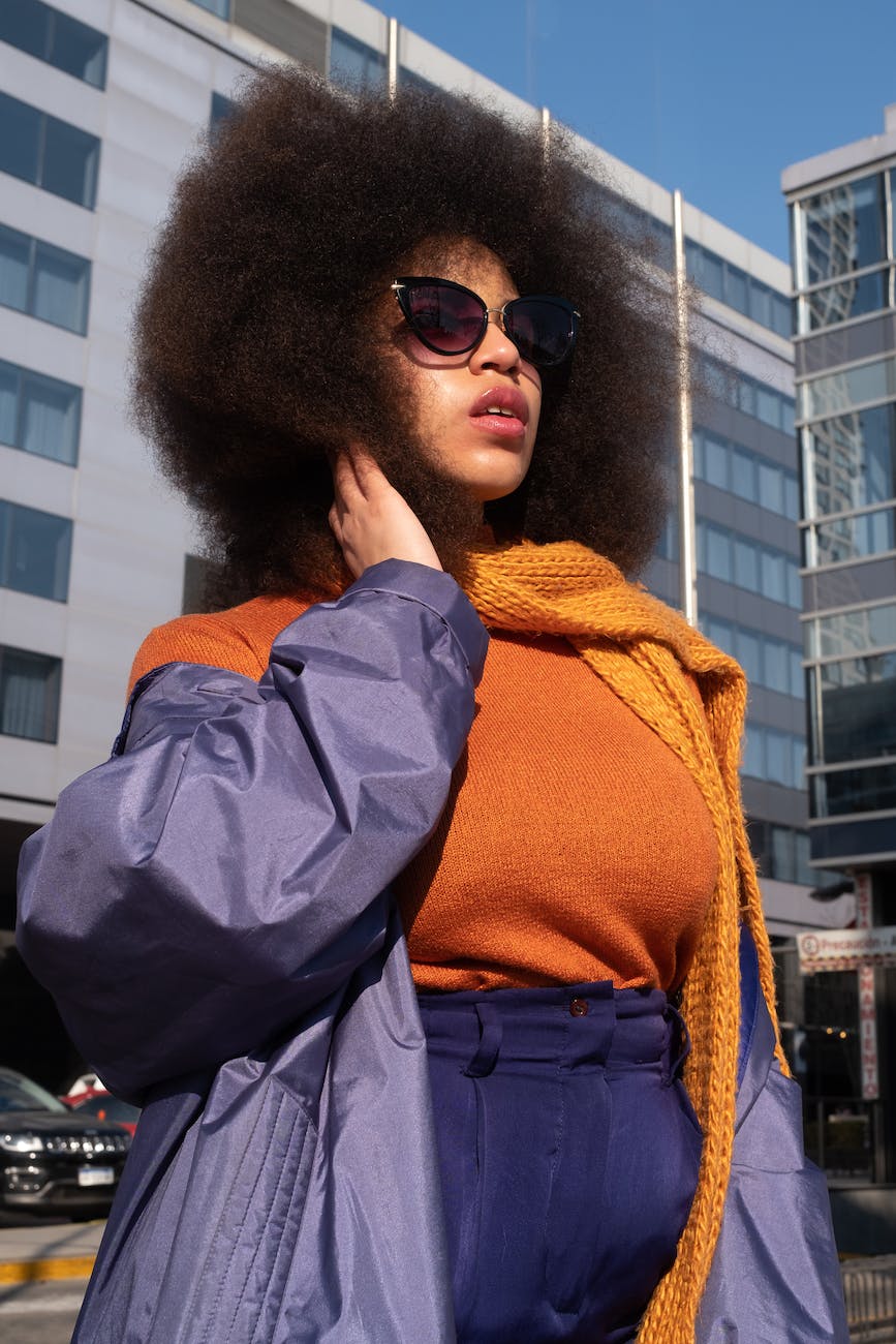 close up of a woman with afro hairstyle wearing purple coat and orange blouse