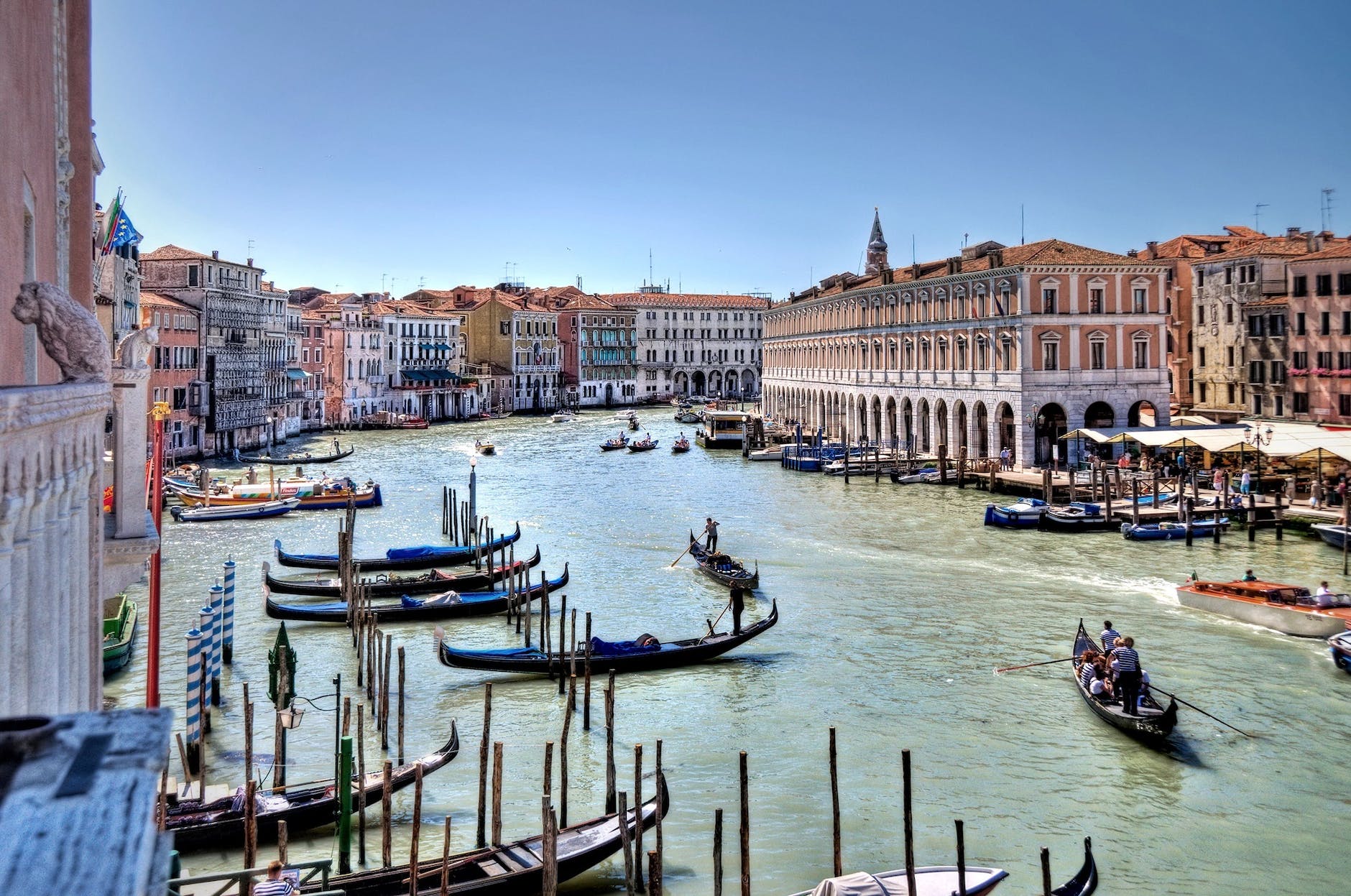 grand canal in venice with people rowing on gondolas beside tall building