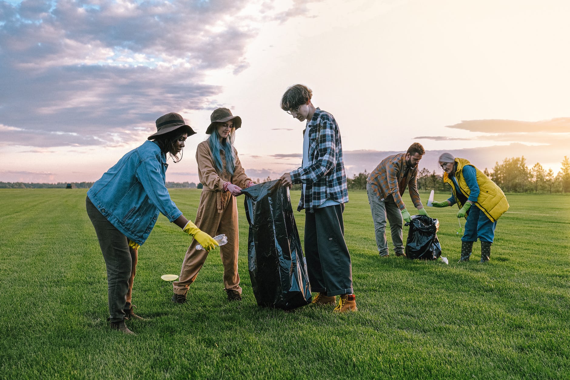 volunteers collecting trash on green grass field