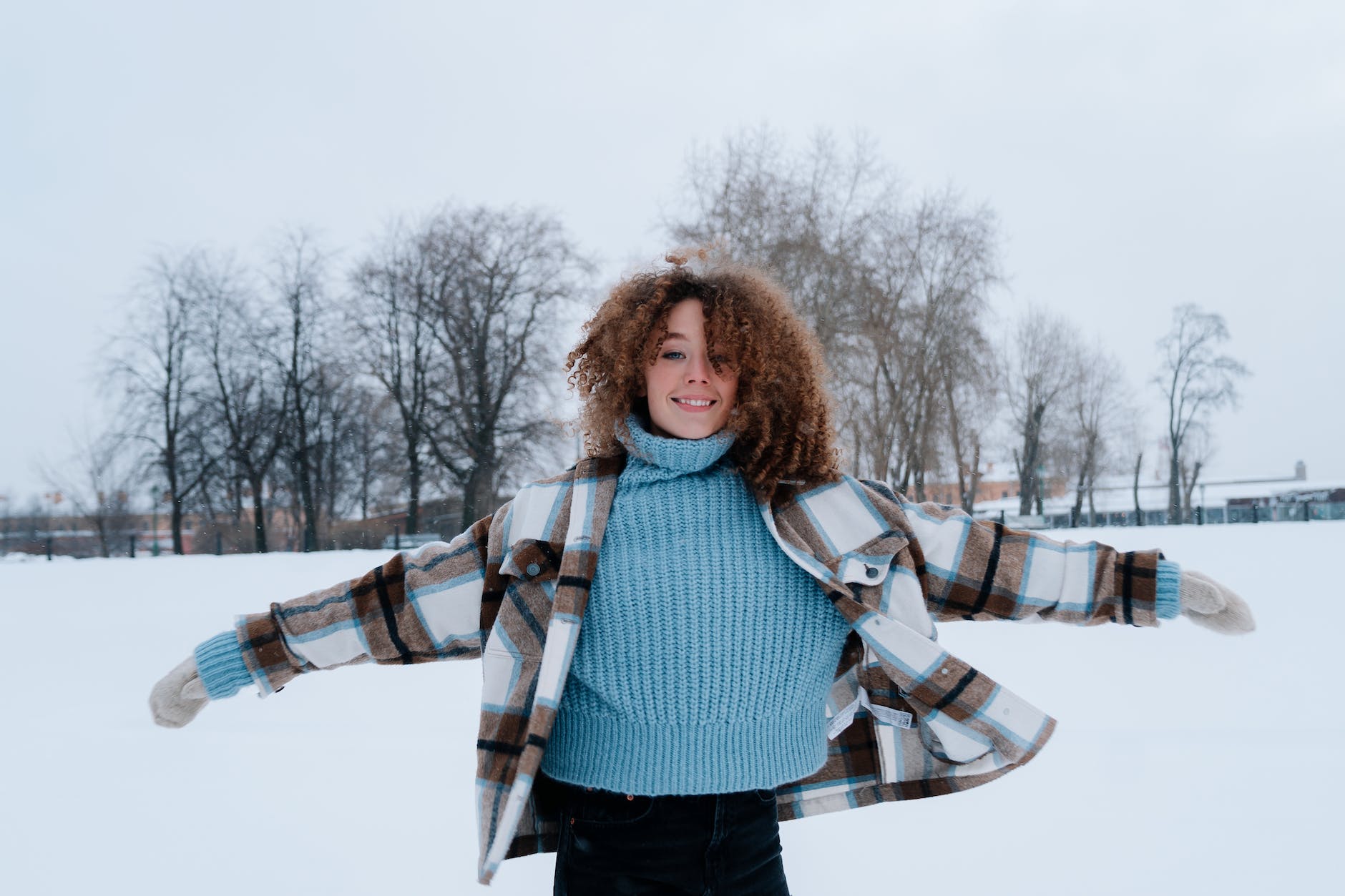 pexels-photo-10453037 woman with curly hair wearing winter clothes playing in snow field